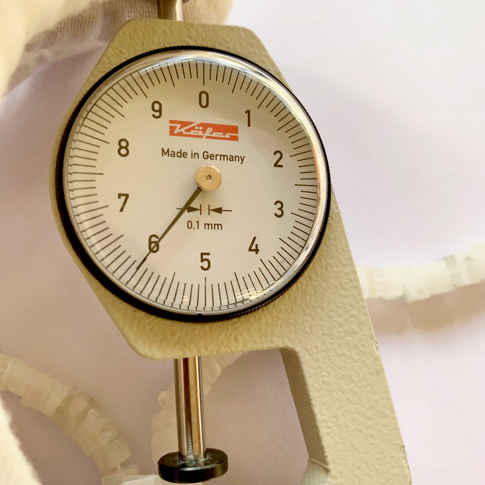 A dial gauge measures the Moonstone heishi square 6–6.5mm gemstone.