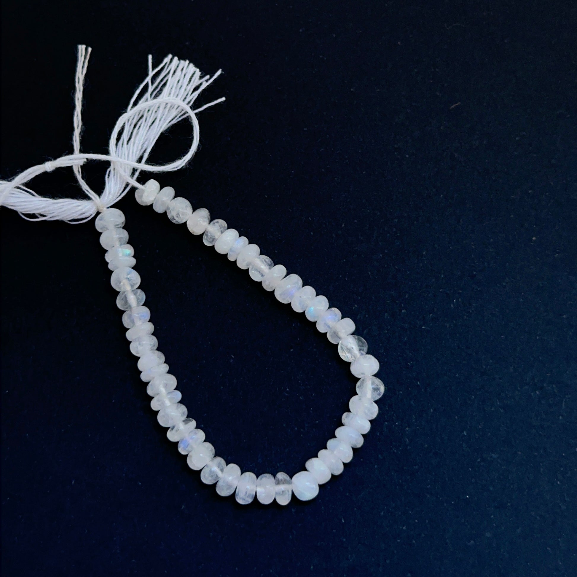 Moonstone smooth rondelle natural gemstone beads with soft glow arranged on a 10cm strand for handmade jewellery components.