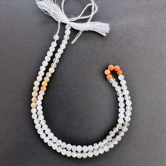 Close-up of Moonstone smooth round beads with soft white tones and blue flashes.