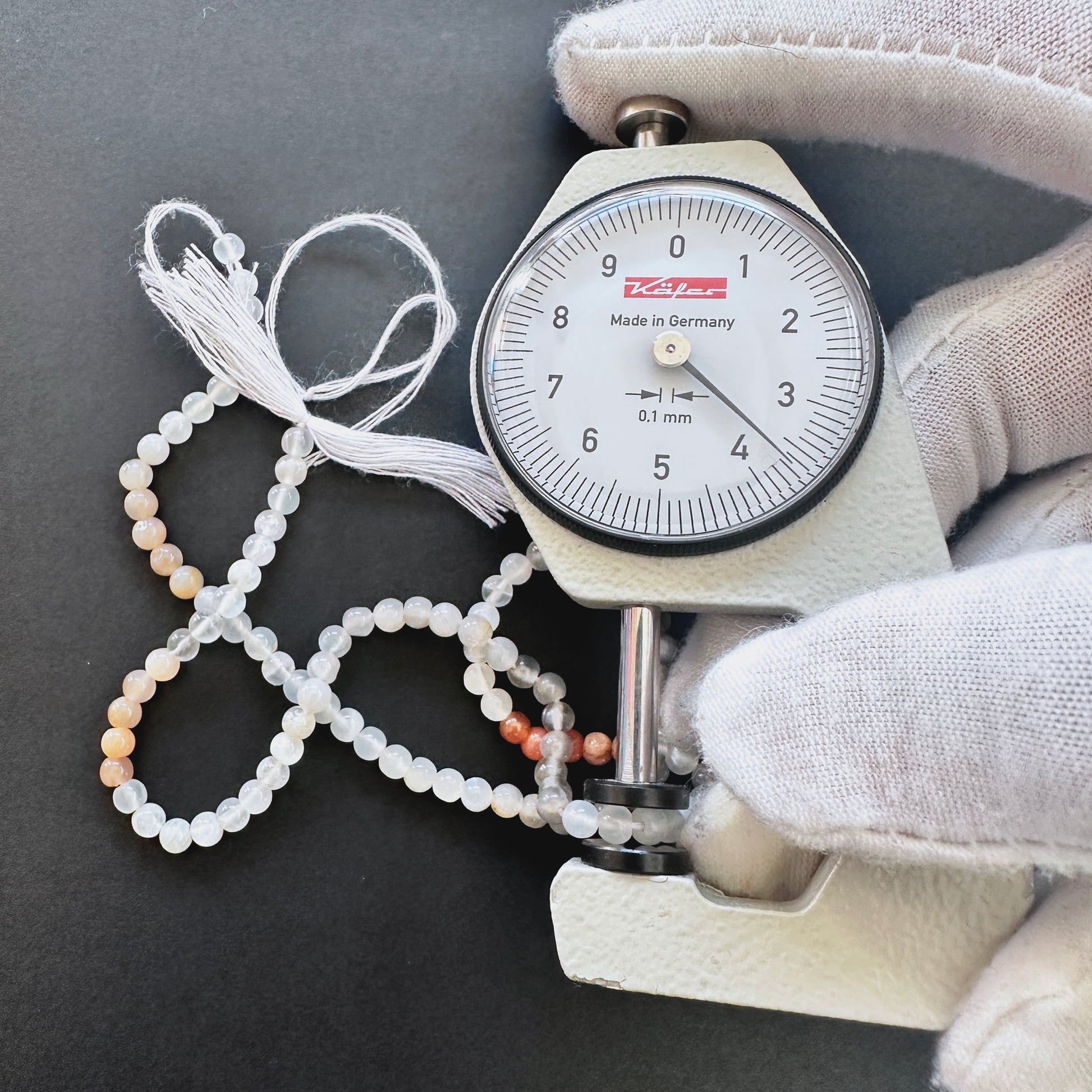 A dial gauge measures the Moonstone smooth round 3.6mm gemstone.