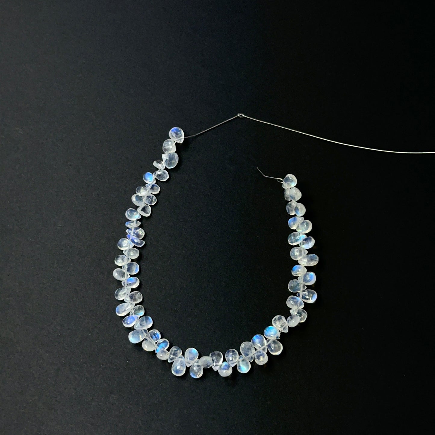 Close view of polished Moonstone smooth teardrops arranged on a 19cm strand for handmade jewellery components.
