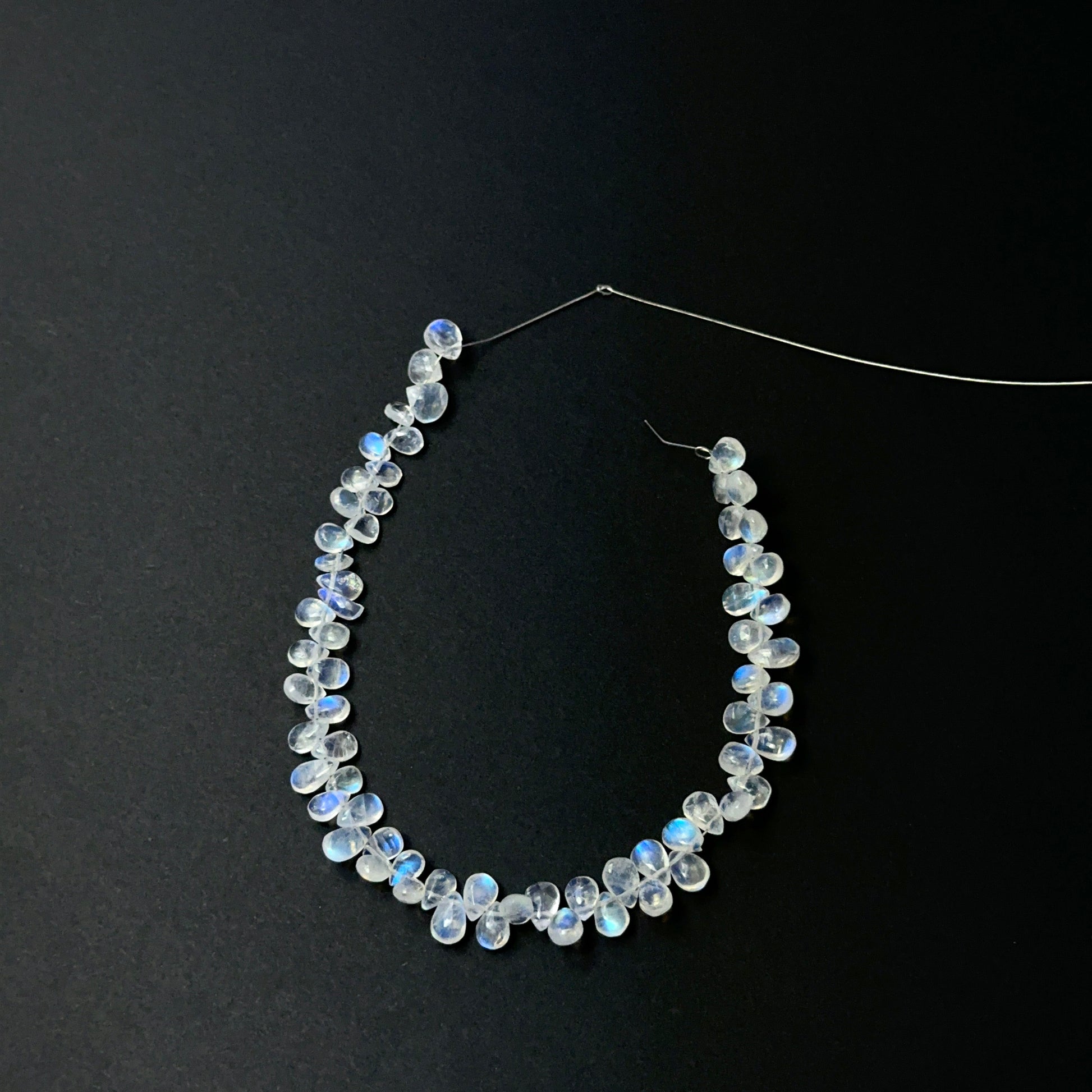 Close view of polished Moonstone smooth teardrops arranged on a 19cm strand for handmade jewellery components.
