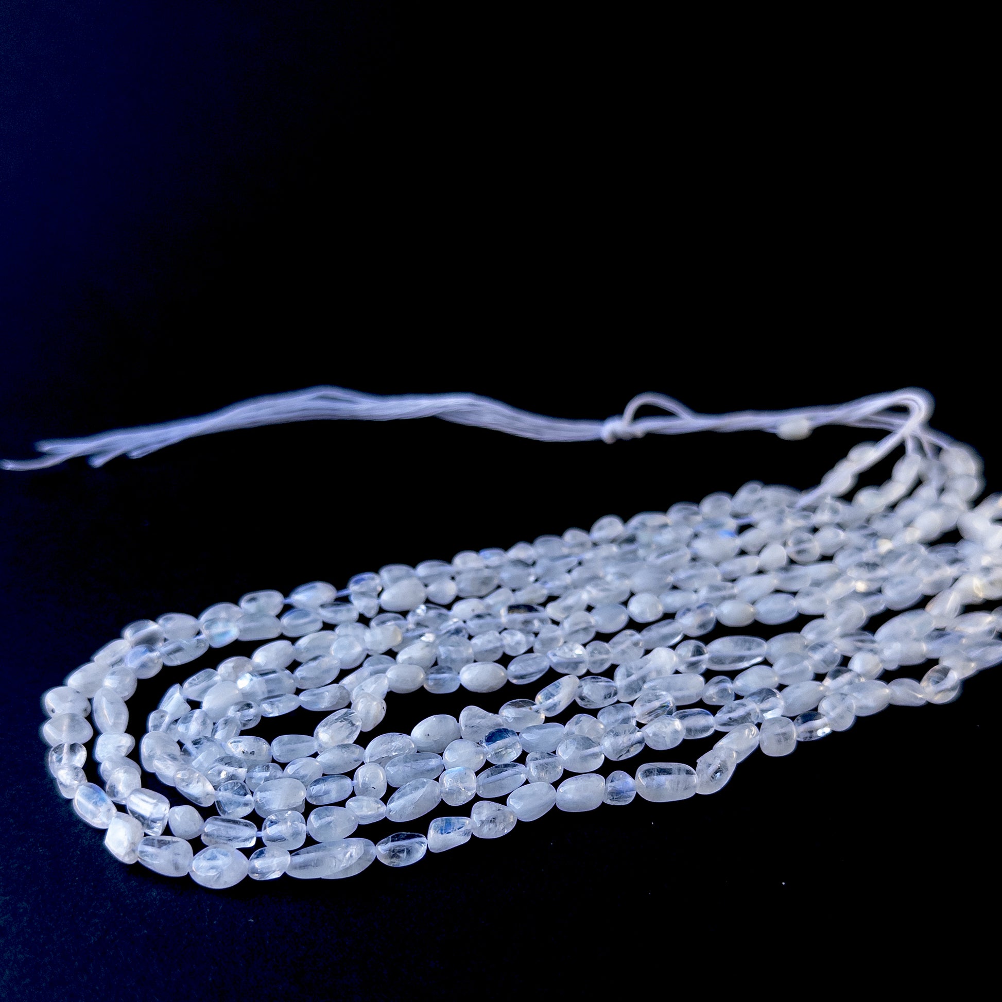 Genuine stone beads with soft white tones and rainbow flashes, featuring smooth tumbles for DIY jewellery making.