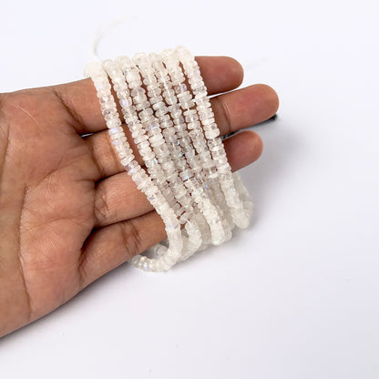 A person holds delicate strands of Moonstone smooth wheel beads, showcasing their polished design.