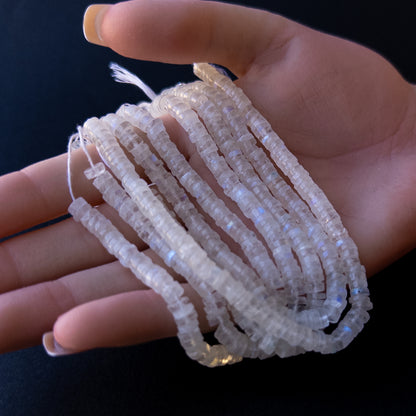 A person holds delicate strands of Moonstone beads, showcasing their smooth wheel design.