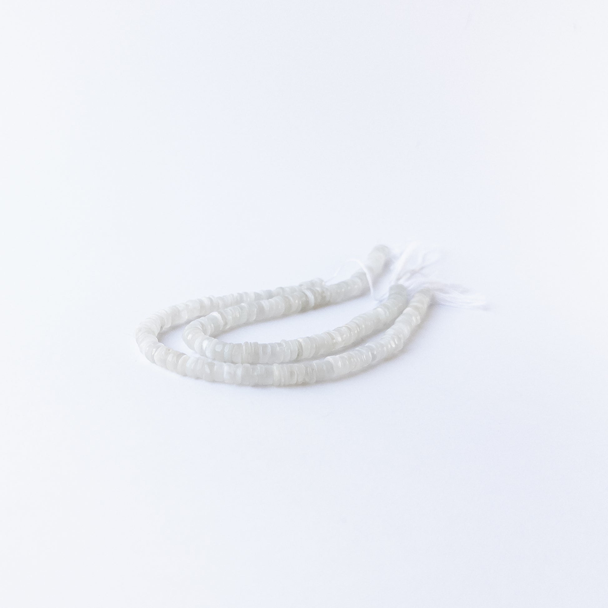 Close‑up of Moonstone smooth wheel beads showing their glow, clarity, and uniform arrangement.