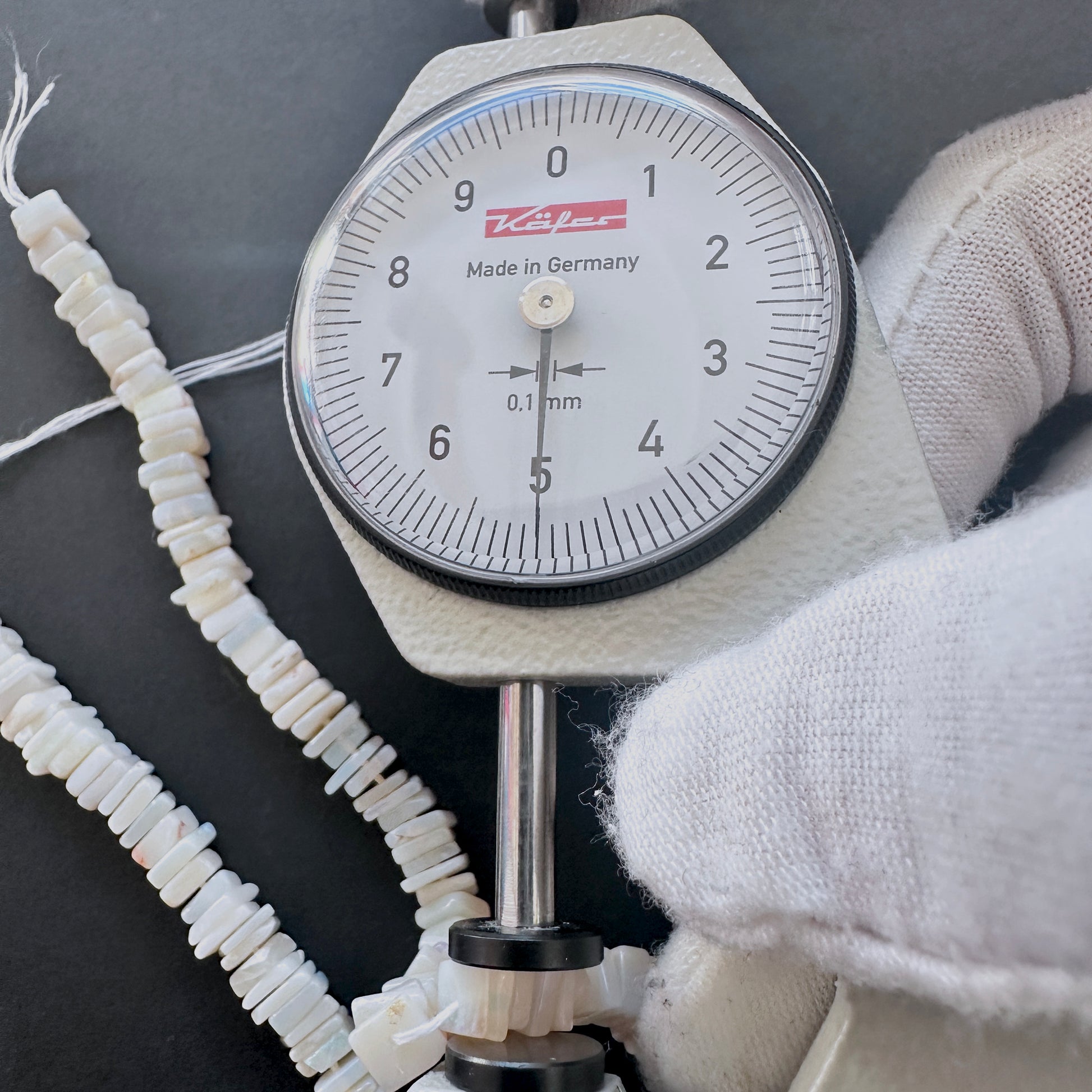 A dial gauge measures the Moonstone square heishi 5mm gemstone.