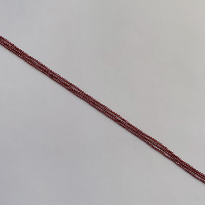 Strands of 2mm Garnet beads reflecting natural light, showing their brilliant cut and colour.
