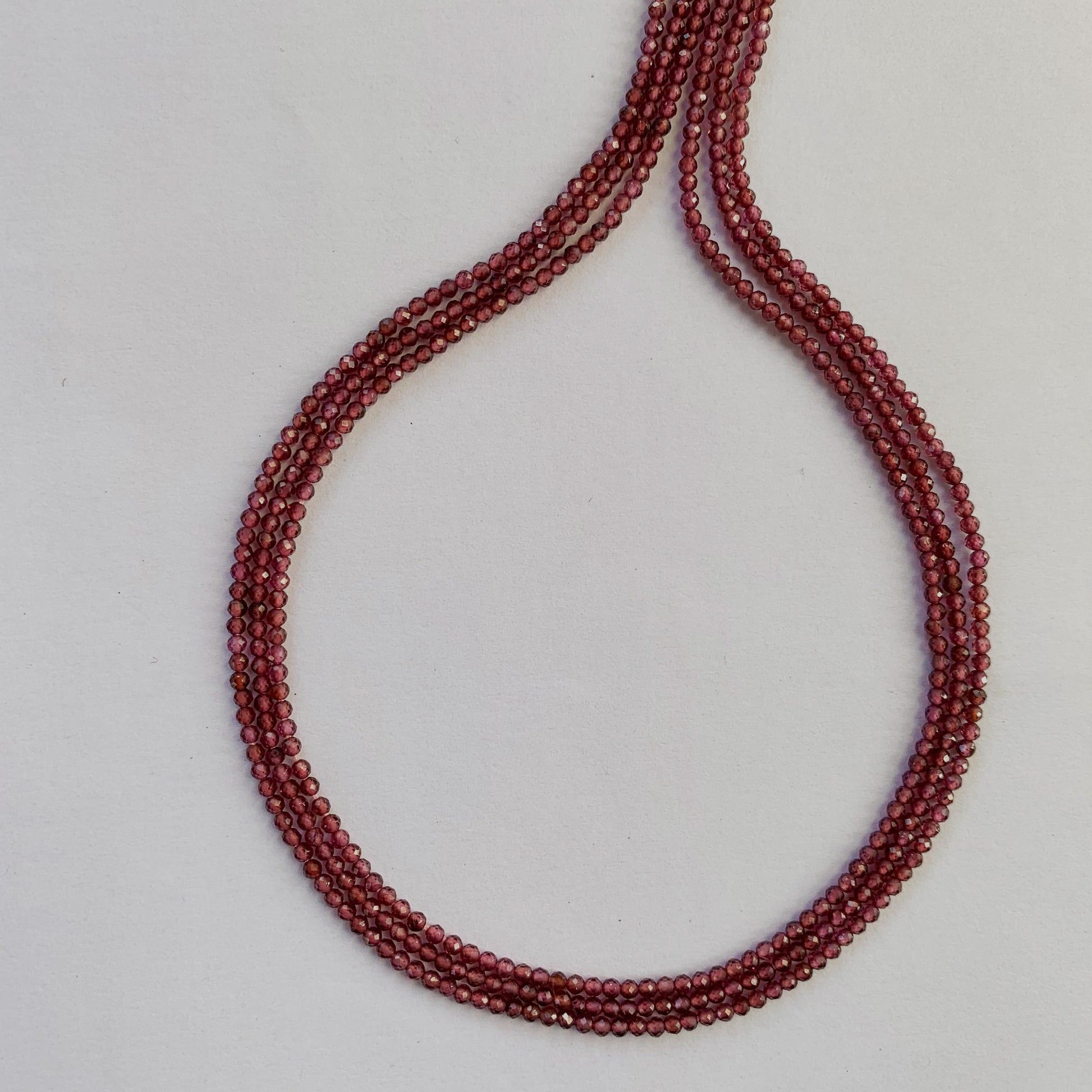 Detailed view of finely faceted Garnet rondelles aligned along a uniform 32cm strand.