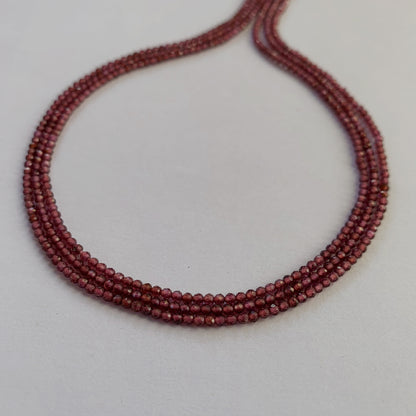 Close-up of deep red Mozambique Garnet gemstones with a precision faceted rondelle cut.