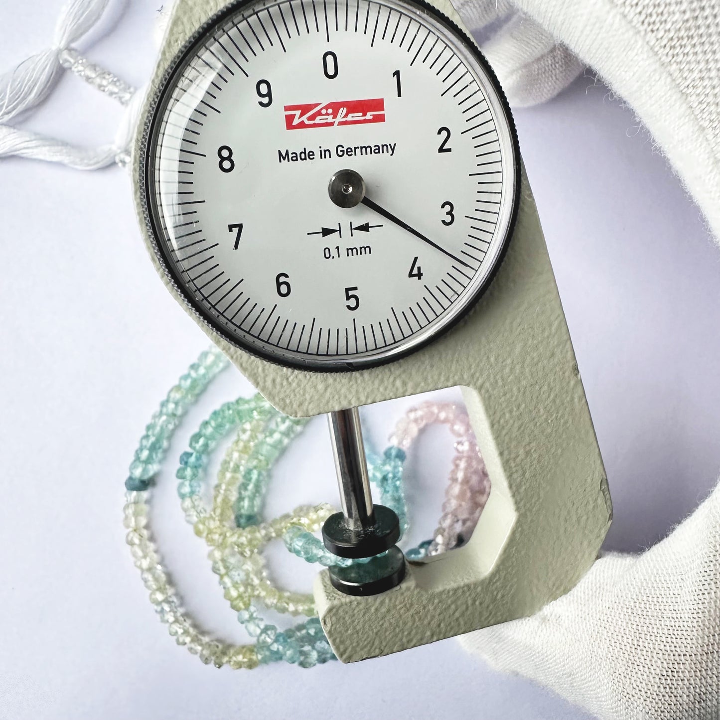 A dial gauge measures the Multi Aquamarine Faceted Rondelle 3.5–4mm gemstone.