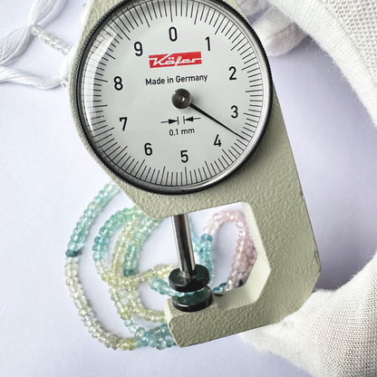 A dial gauge measures the Multi Aquamarine Faceted Rondelle 3.5–4mm gemstone.