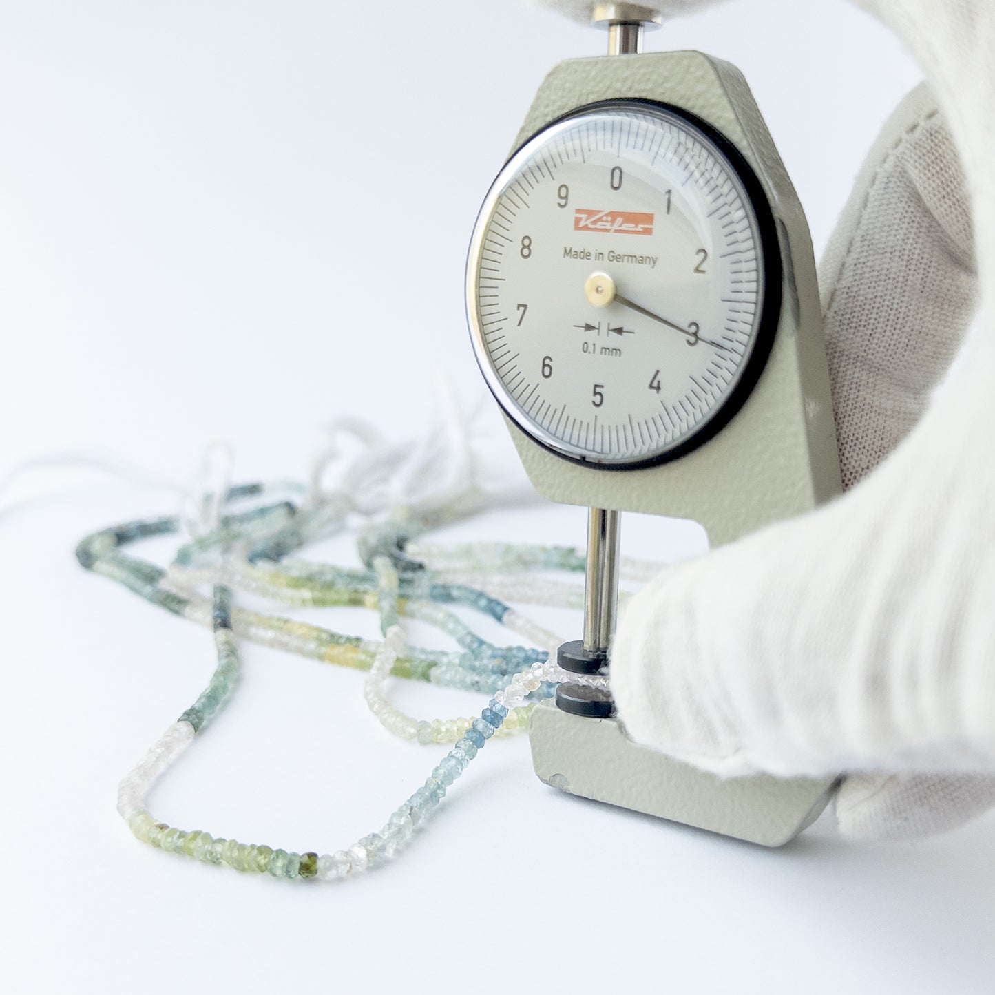 A dial gauge measures the Multi Aquamarine faceted rondelle 3mm gemstone.