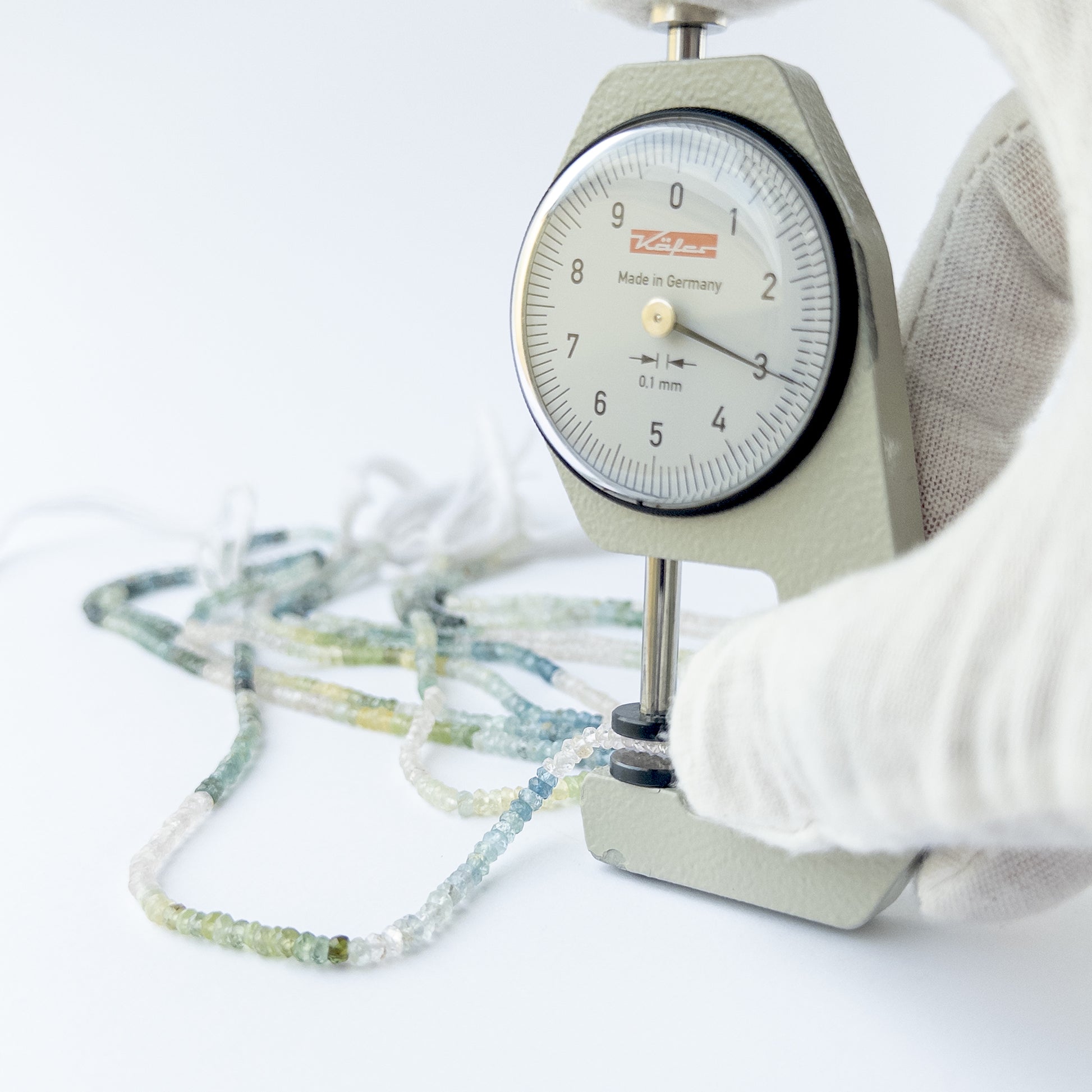 A dial gauge measures the Multi Aquamarine faceted rondelle 3mm gemstone.