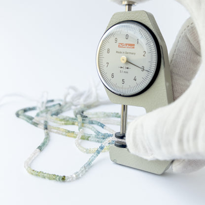 A dial gauge measures the Multi Aquamarine faceted rondelle 3mm gemstone.