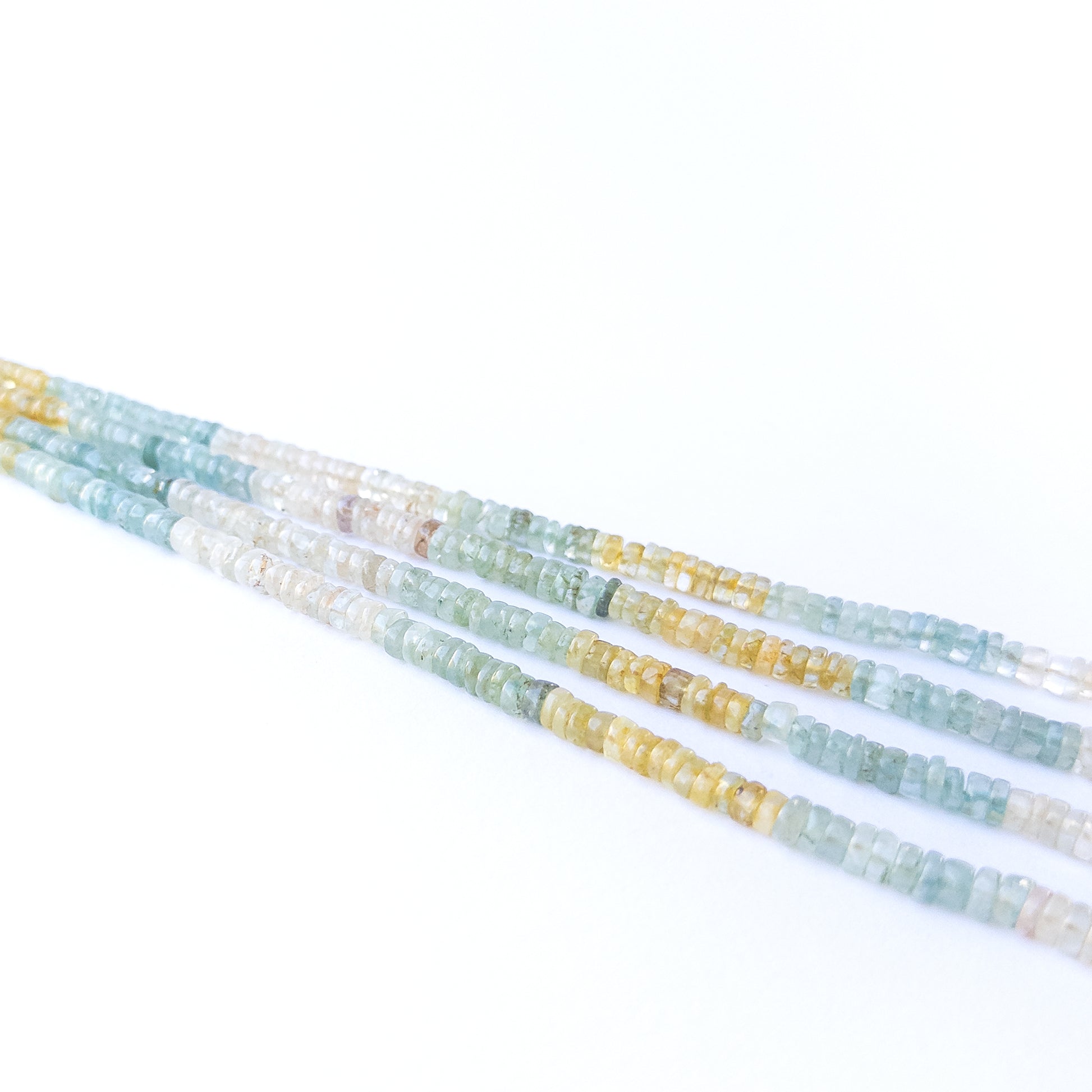 Close‑up of Multi Aquamarine smooth wheel beads showing their clarity, shine, and uniform arrangement.