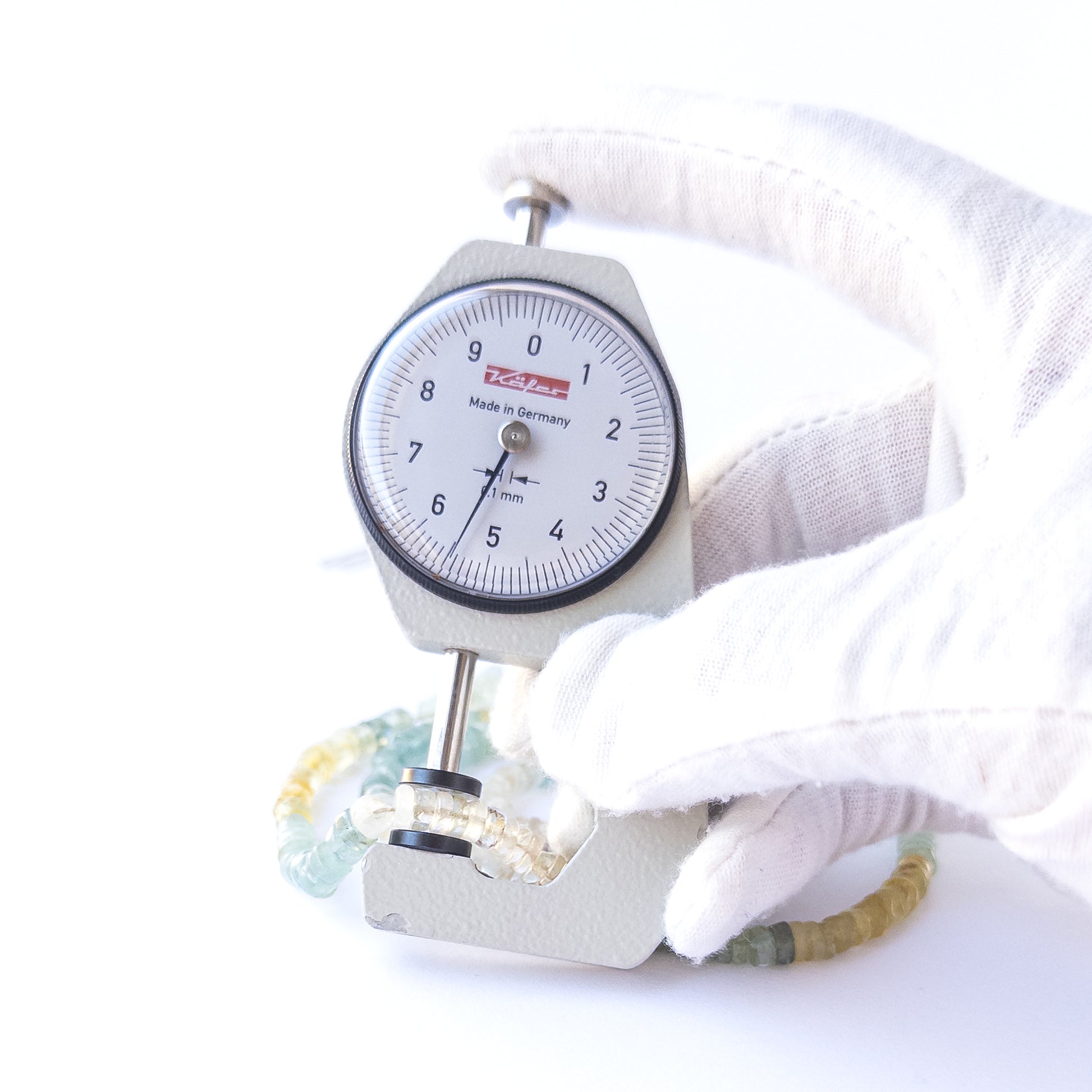 A dial gauge measures the Multi Aquamarine smooth wheels heishi 5–5.5mm gemstone.  