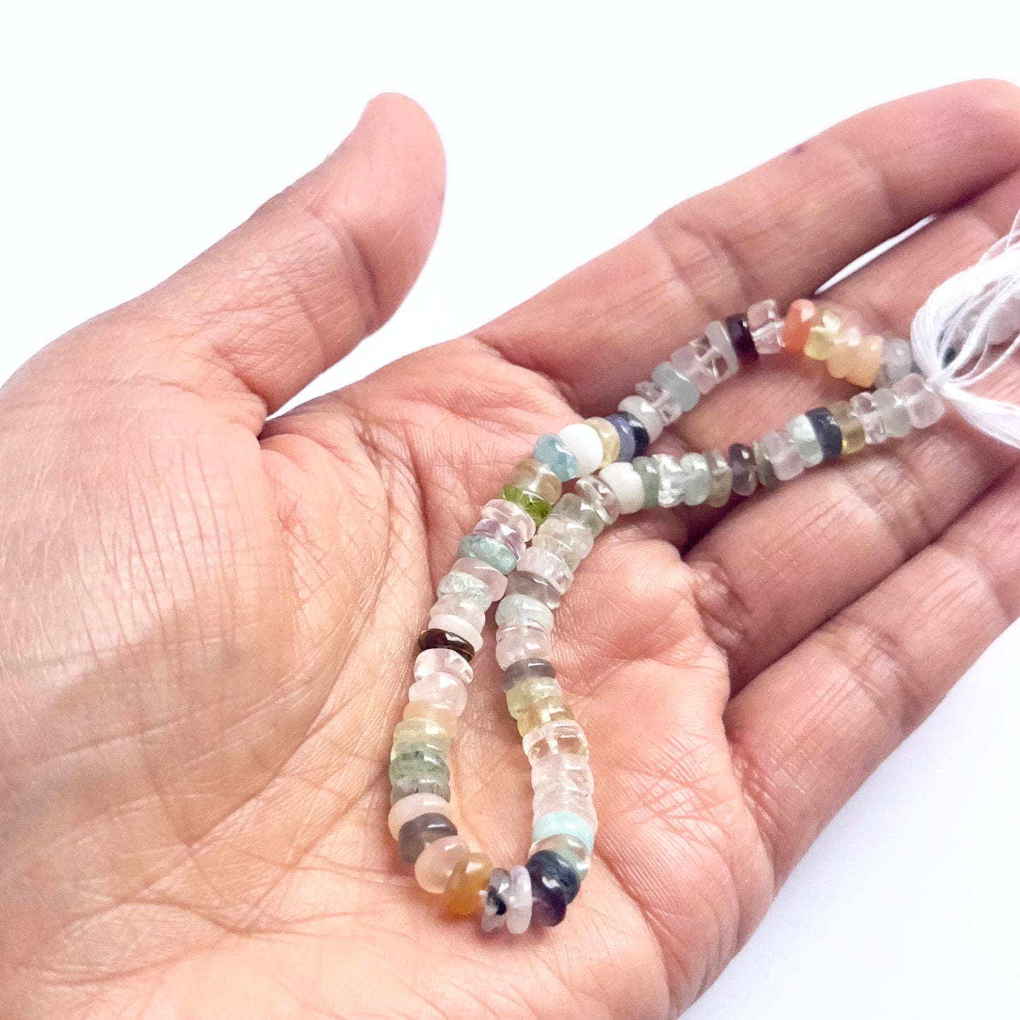 A person holds delicate strands of Multi Disco beads, showcasing their smooth design.
