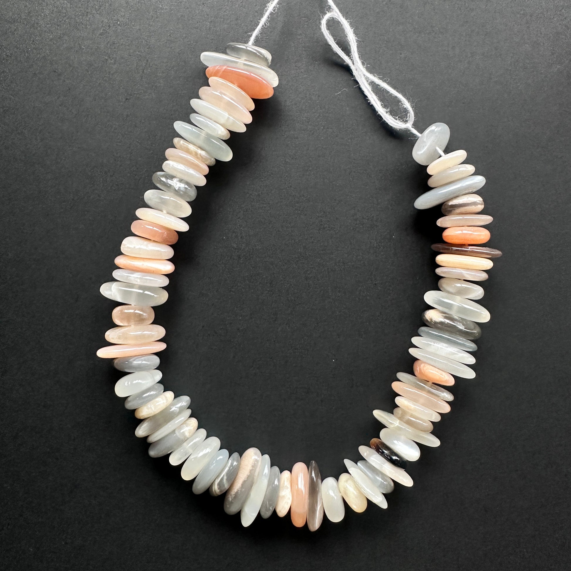 Natural gemstone beads with soft grey and peach tones, arranged in a smooth polished strand.