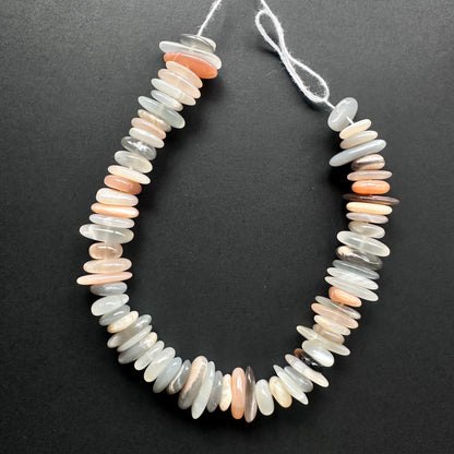 Natural gemstone beads with soft grey and peach tones, arranged in a smooth polished strand.