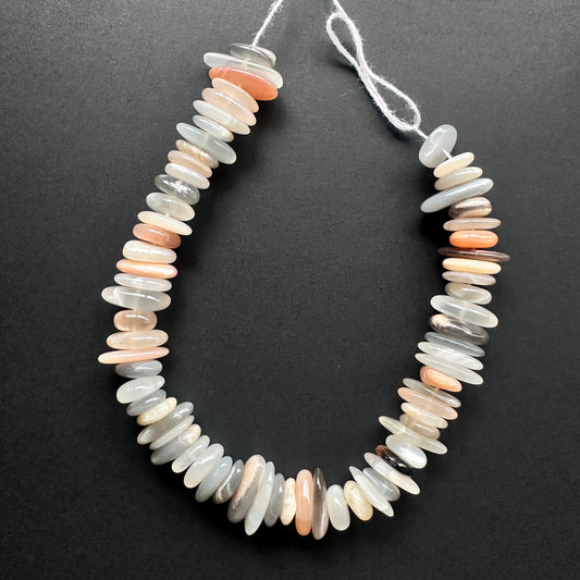 Natural gemstone beads with soft grey and peach tones, arranged in a smooth polished strand.