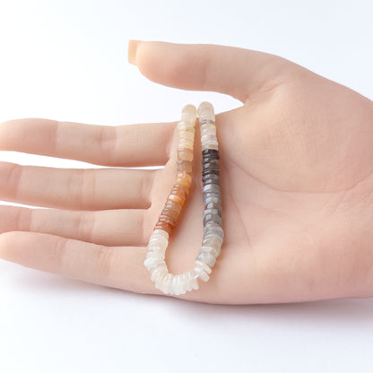 A person holds delicate strands of Multi Moonstone beads, showcasing their smooth wheel design.
