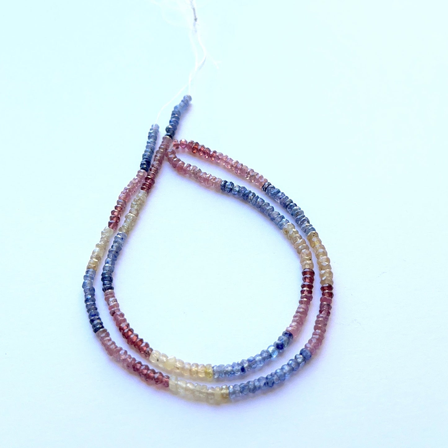 Close‑up of mixed ruby, yellow sapphire and blue sapphire 2.8–3.2mm faceted rondelle beads highlighting precise facets and bright hue