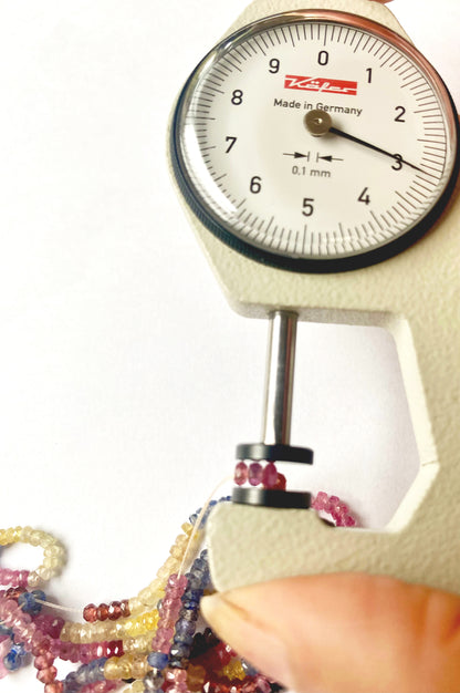 A dial gauge measures the Multi Precious faceted rondelle 2.8mm gemstone.