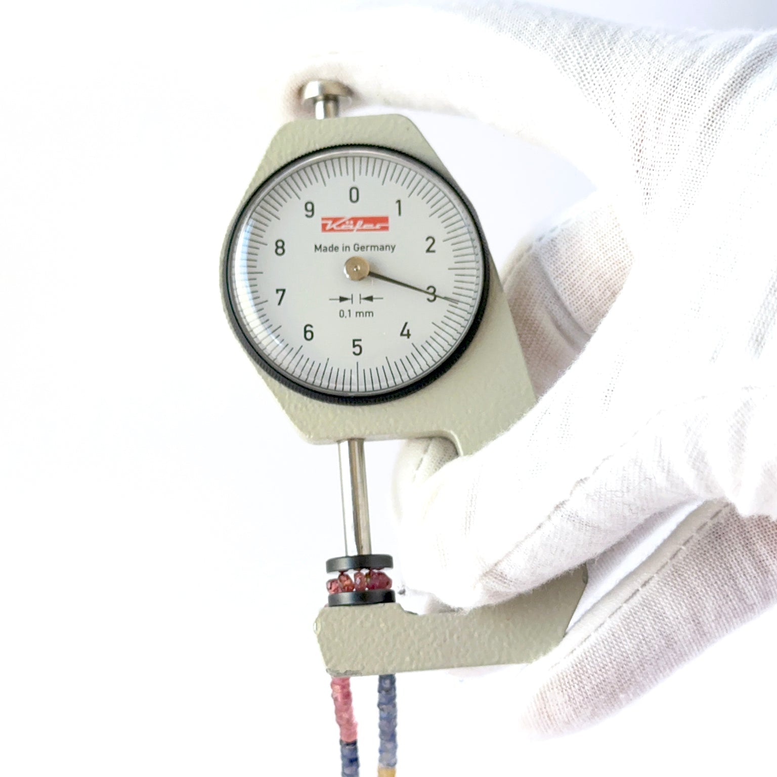 A dial gauge measures the Multi Precious faceted rondelle 2.8–3.2mm gemstone.