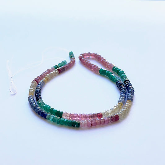 Close‑up of mixed ruby, yellow sapphire, blue sapphire and emerald 3.3–4mm faceted rondelle beads showing vivid colour and sparkle.