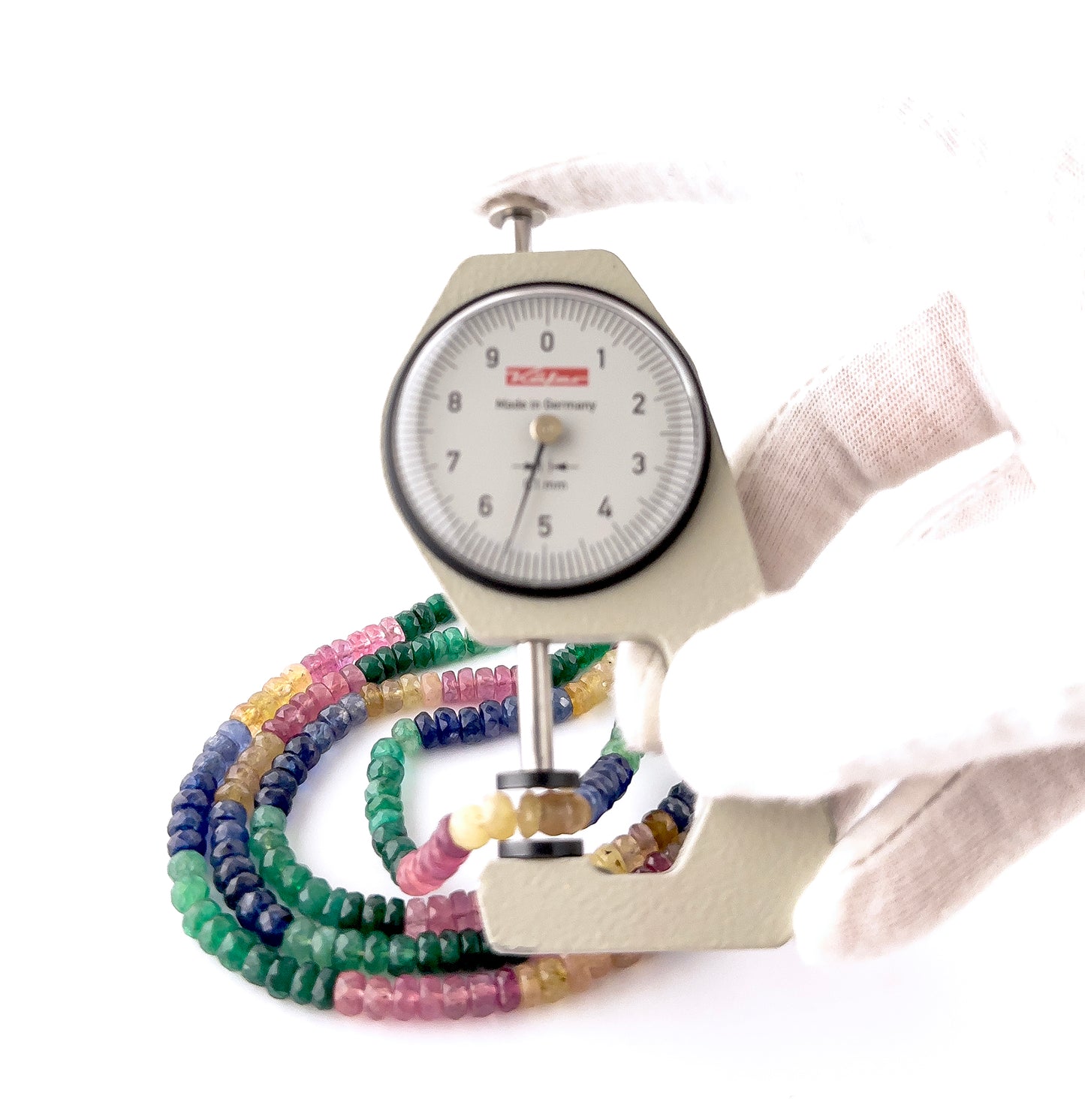 A dial gauge measures the multi precious faceted rondelle 5–5.5mm gemstone.
