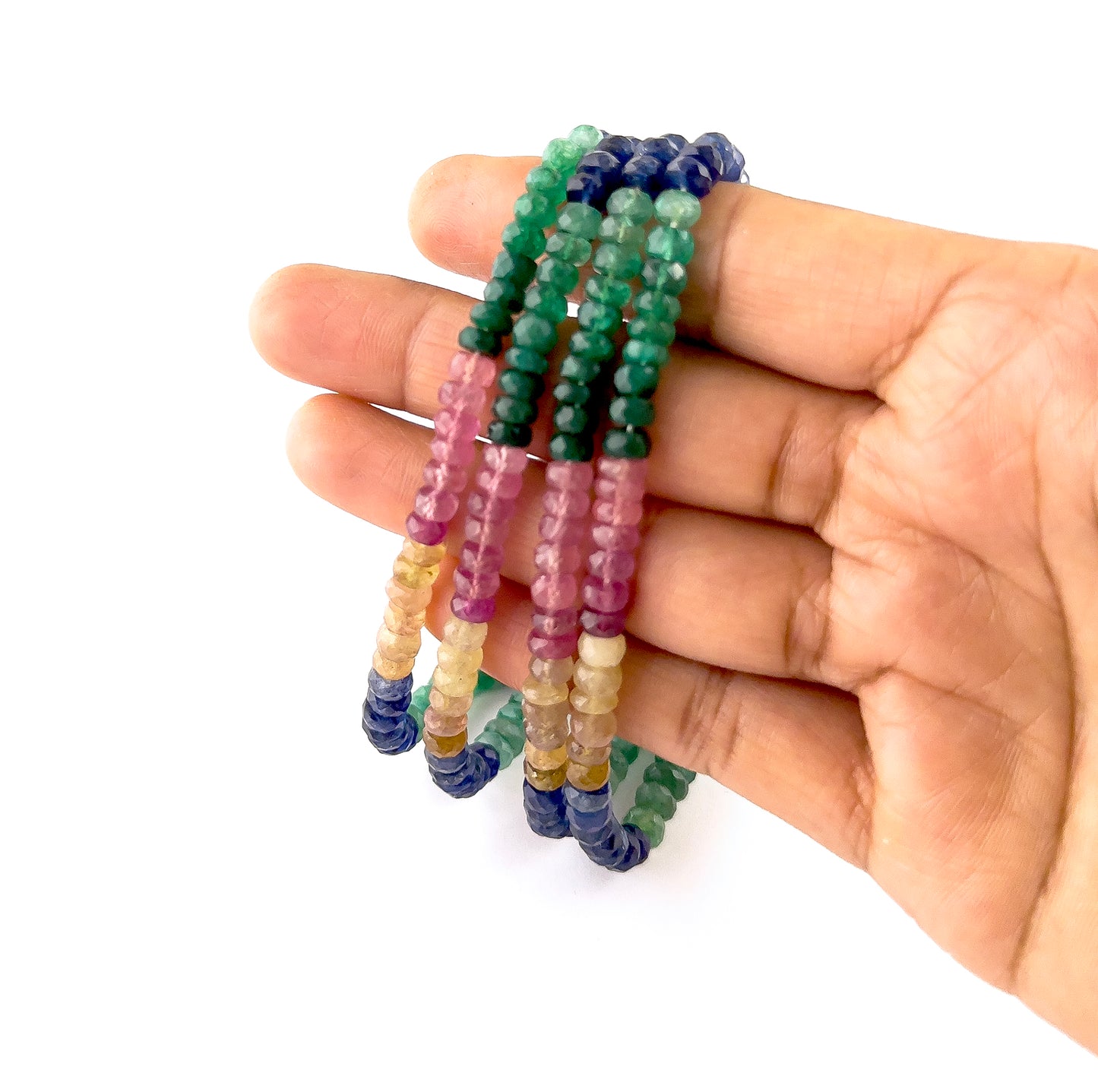 A person holds multi precious gemstone rondelle beads, showing their faceted design and colour variation.