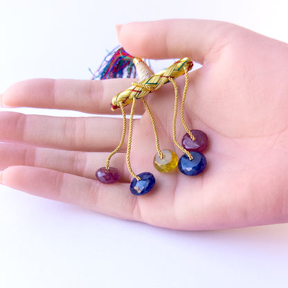 A person holds pieces of Multi Precious beads, showcasing their faceted rondelle design.