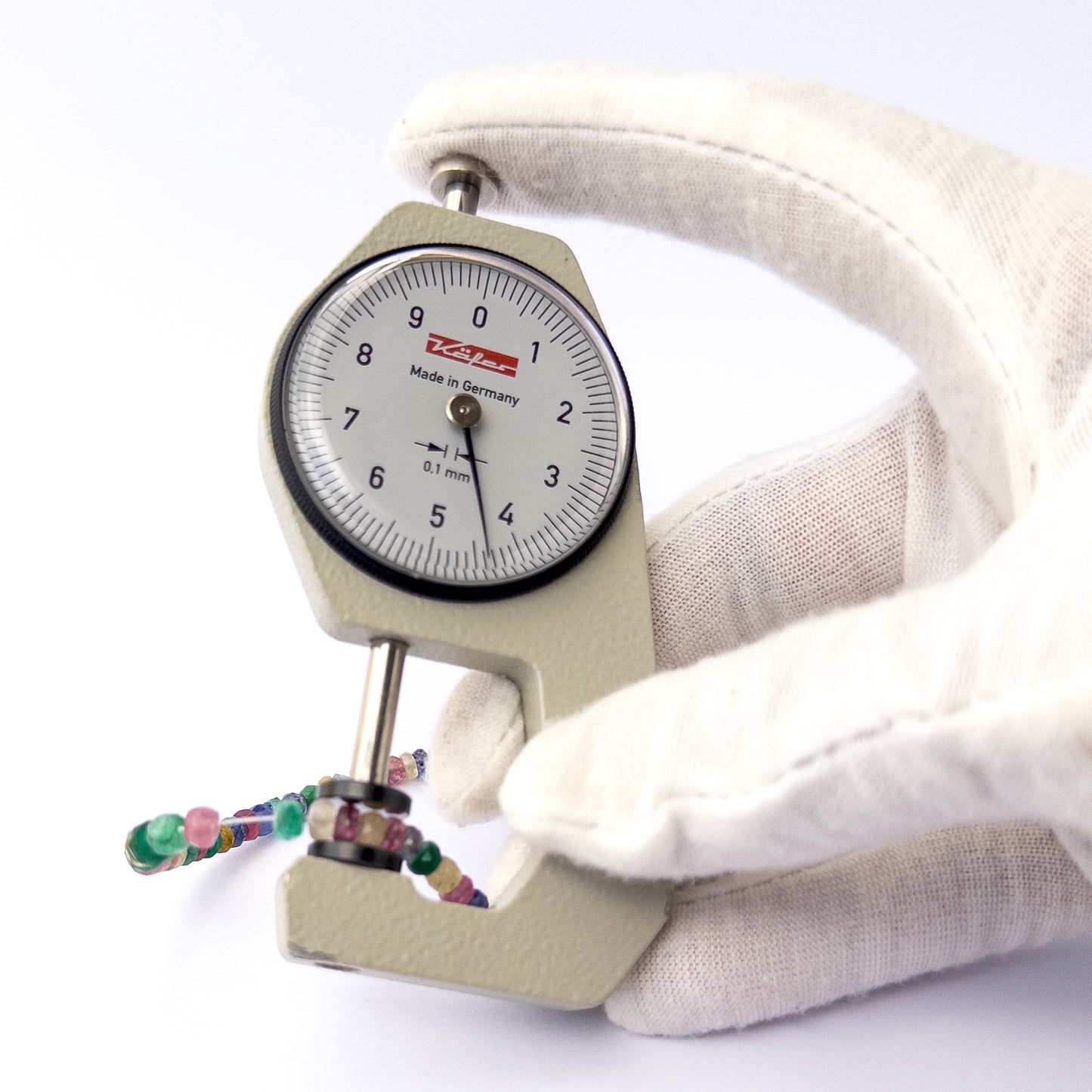 A dial gauge measures the Multi Precious faceted rondelle 3.1–4.5mm gemstone.