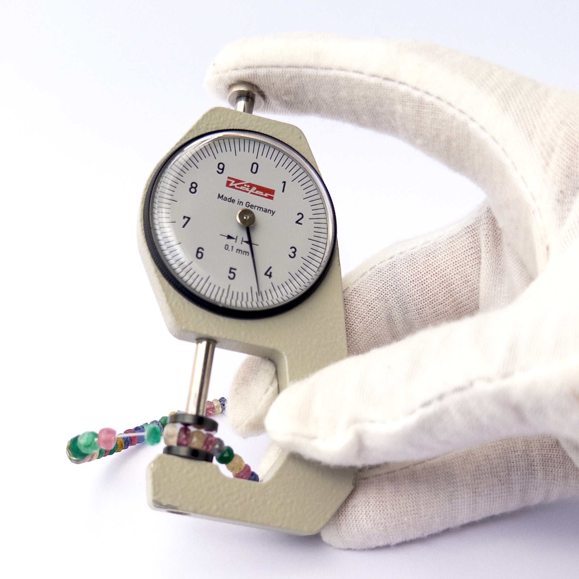 A dial gauge measures the Multi Precious faceted rondelle 3.1–4.5mm gemstone.