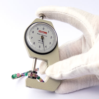 A dial gauge measures the Multi Precious faceted rondelle 3.1–4.5mm gemstone.