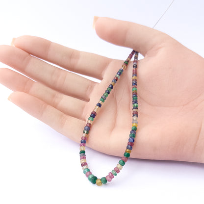 A person holds delicate strands of Multi Precious beads, showcasing their faceted rondelle design.