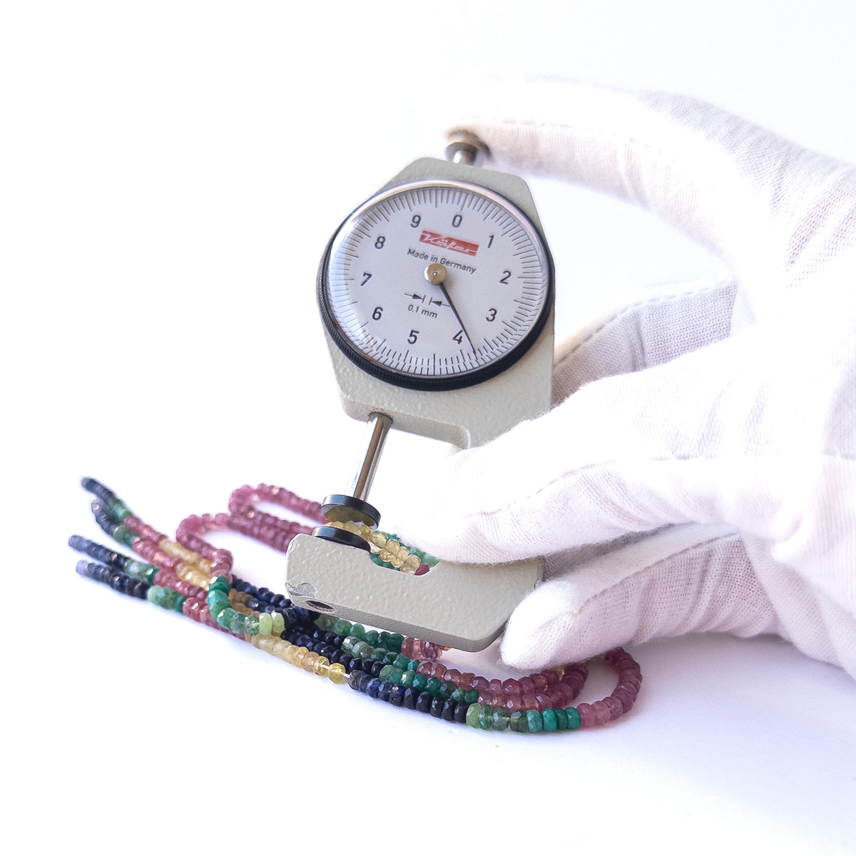 A dial gauge measures the Multi Precious faceted rondelle 3.2–4mm gemstone.