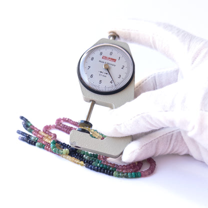 A dial gauge measures the Multi Precious faceted rondelle 3.2–4mm gemstone.