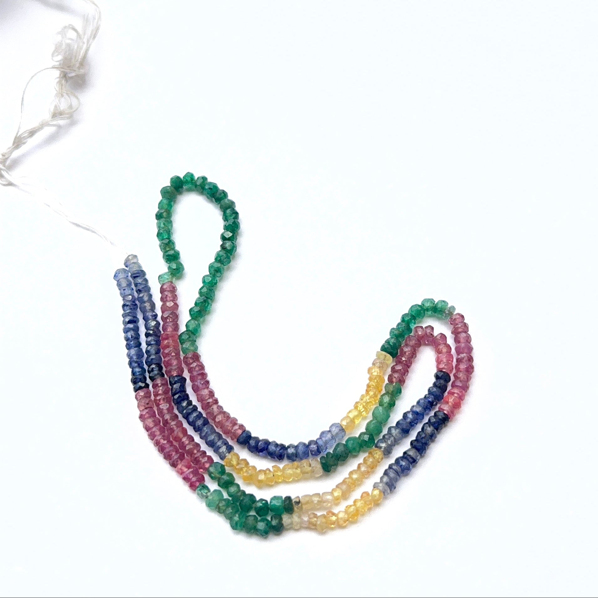 Gemstone strand with ruby, emerald and sapphire rondelles showing bright shine.