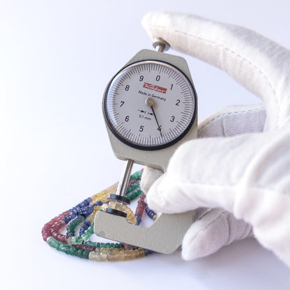 A dial gauge measures the Multi Precious faceted rondelle 2.8–4mm gemstone.