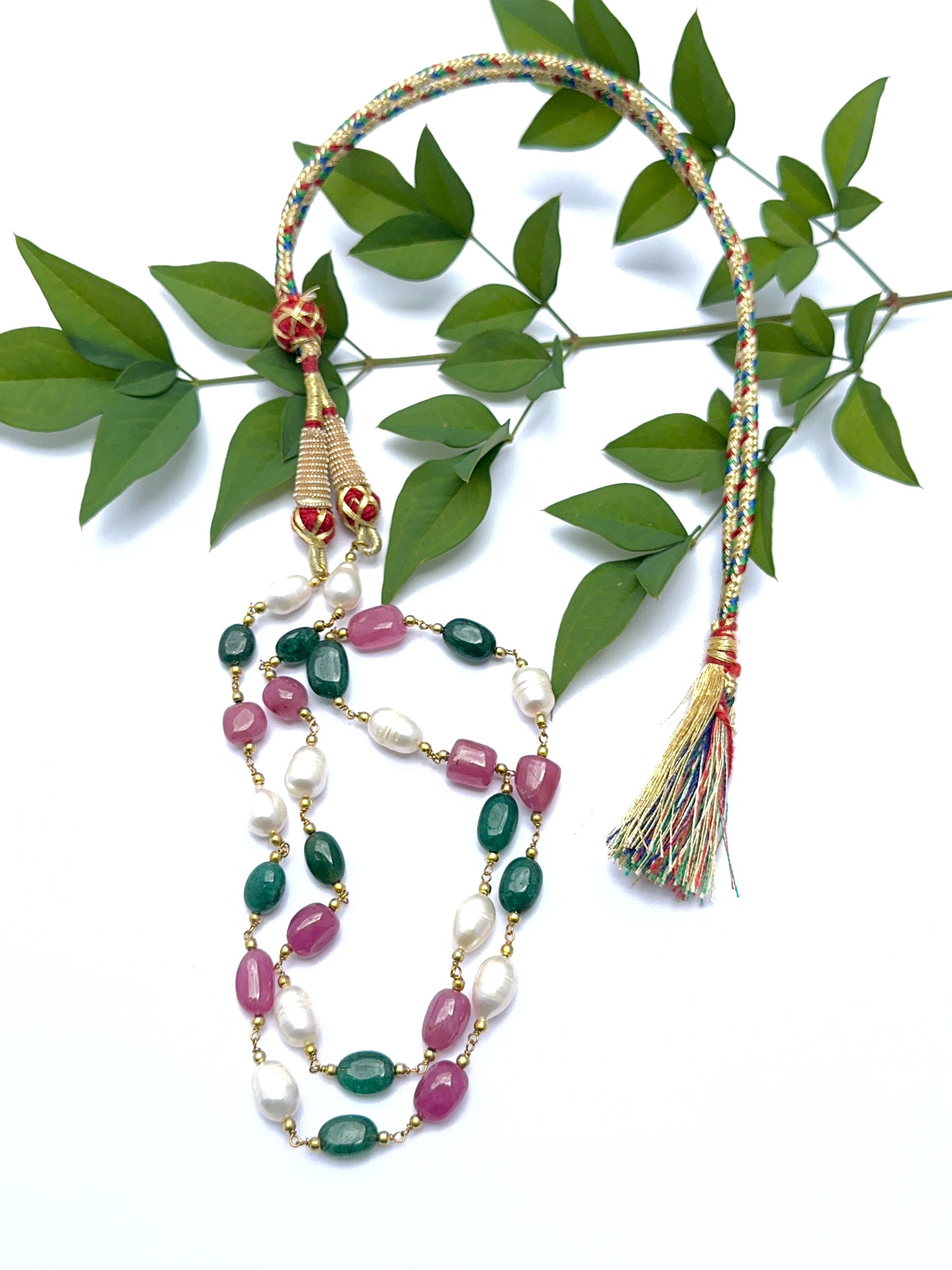 Ruby, emerald and pearl necklace with smooth tumble beads arranged in a balanced layout.
