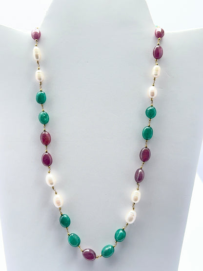 Close‑up of ruby, emerald and pearl beads arranged on a polished finished necklace.