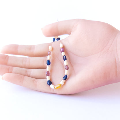 A person holds delicate strands of multi precious and freshwater pearl beads, showcasing their smooth oval design.