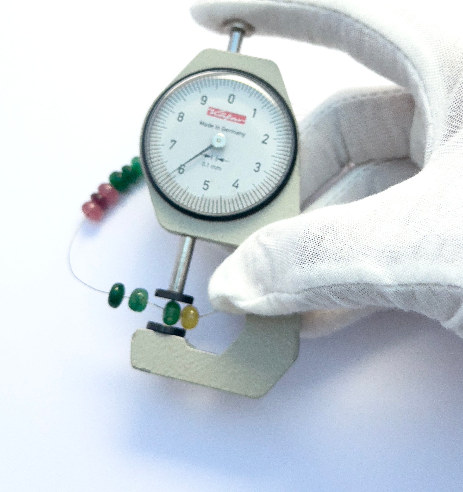 A dial gauge measures the multi-precious rondelle 6.2–6.7mm gemstone.