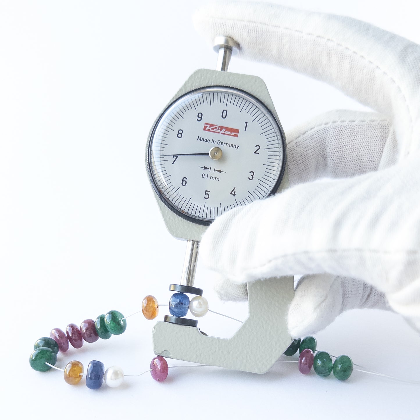 A dial gauge measures the multi precious smooth rondelle 7.2–7.8mm gemstone.