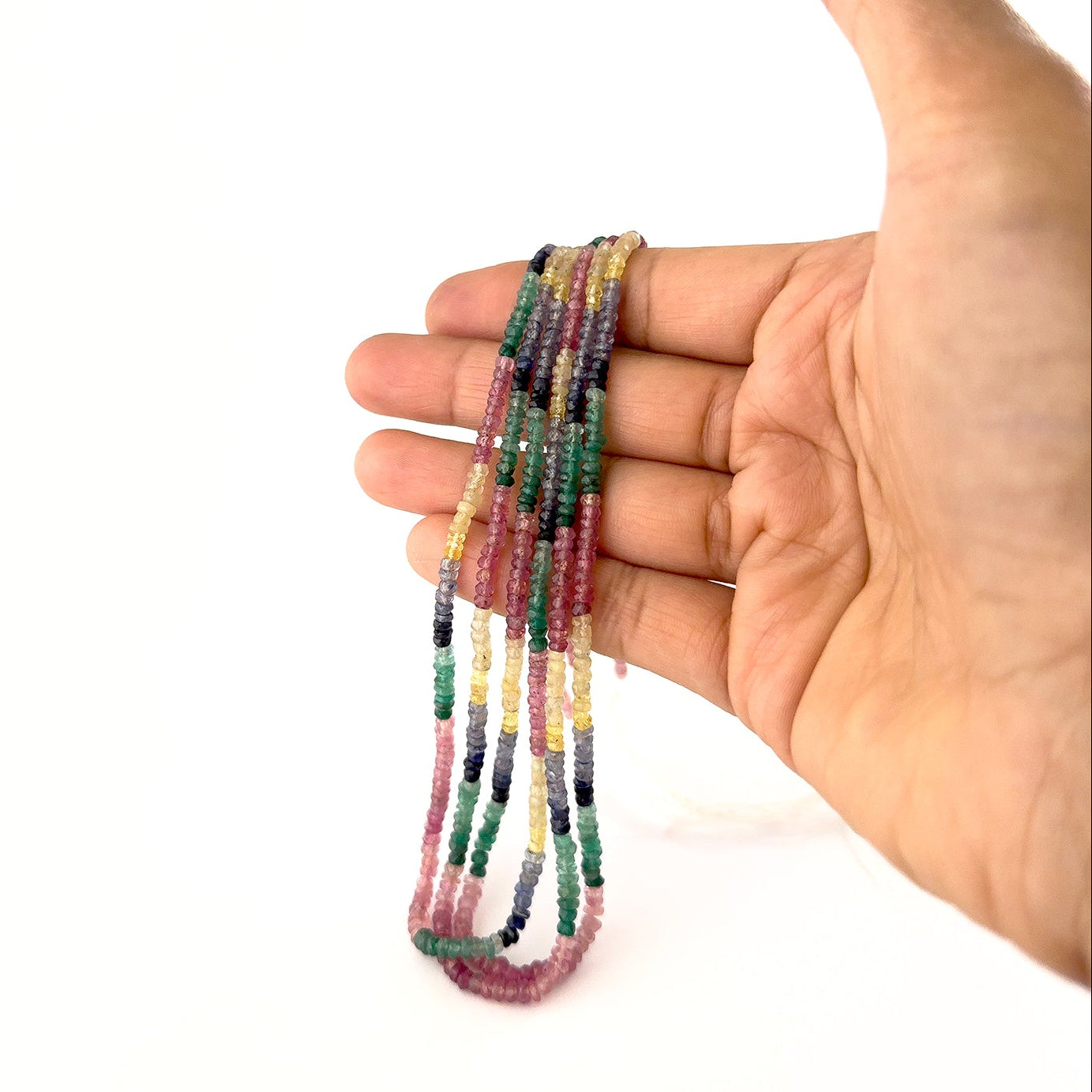 A person holds Multi Precious gemstone rondelle beads, showing their faceted design and colour variation.