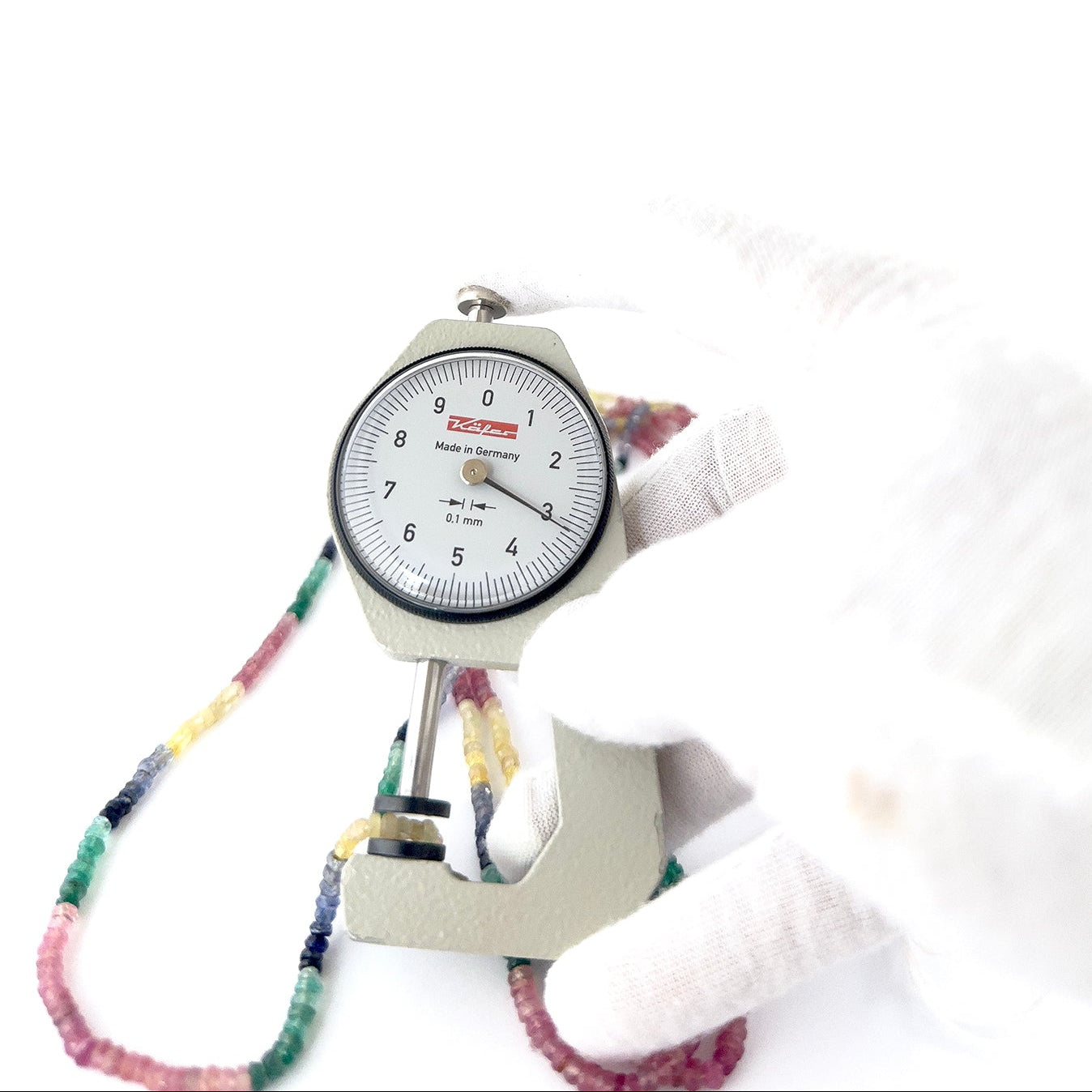 A dial gauge measures the Multi Precious faceted rondelle 3–3.5mm gemstone.