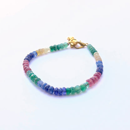 Close‑up of sparkling multi gemstone rondelles arranged on a polished bracelet.