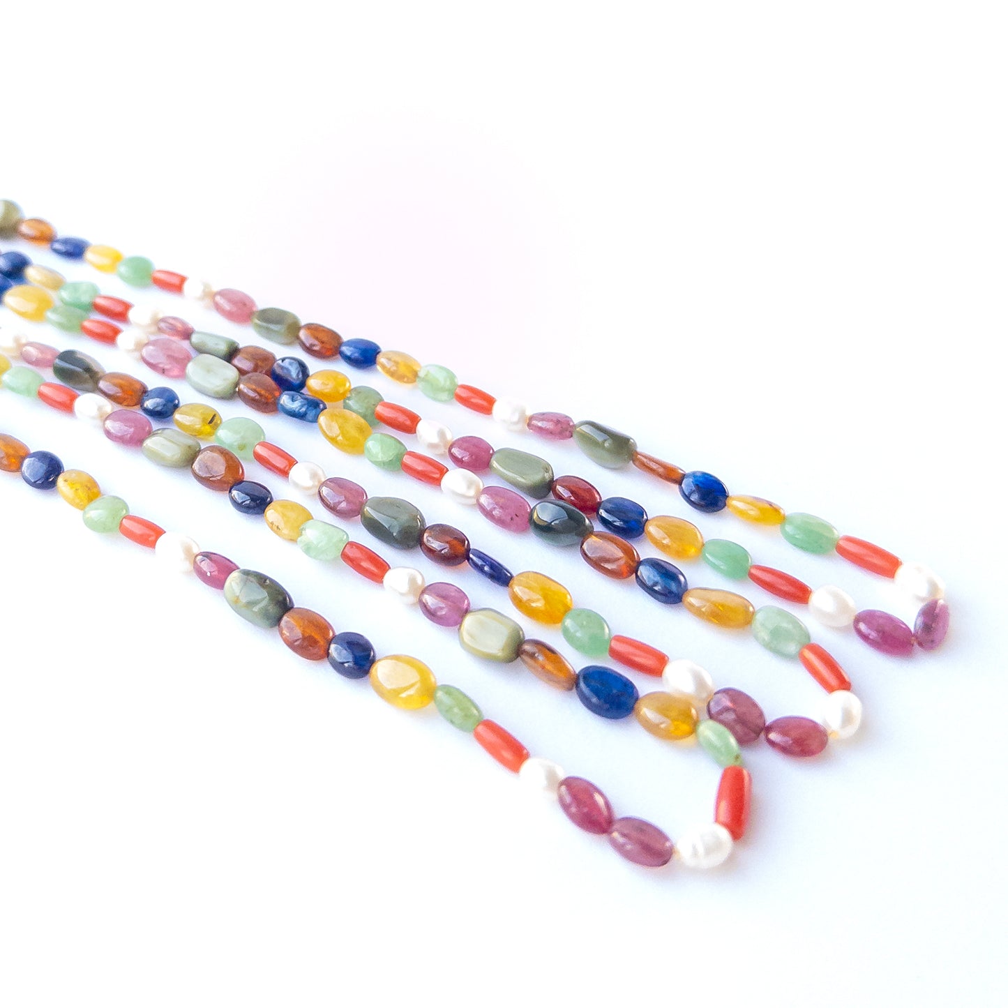Close‑up of Navratan oval beads showing their shine, clarity and rich traditional gemstone variety.